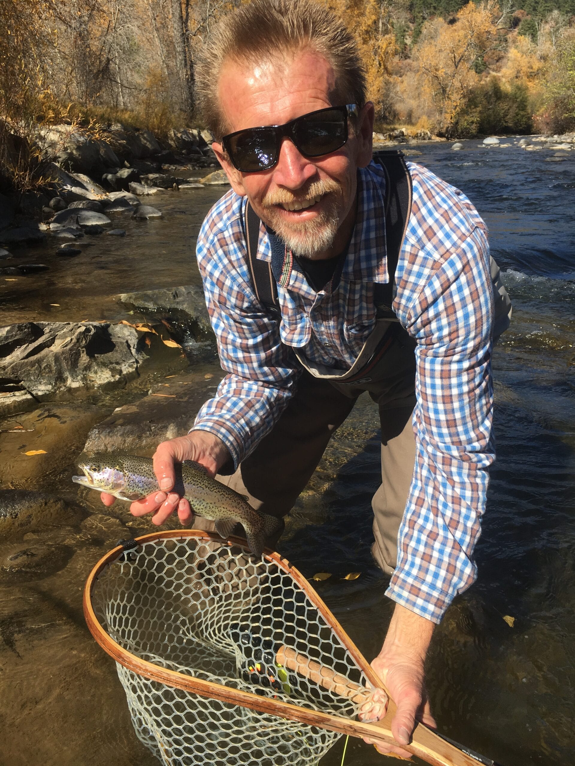Angler netting trout on guided fly fishing trip San Juan River Pagosa Springs Colorado fall