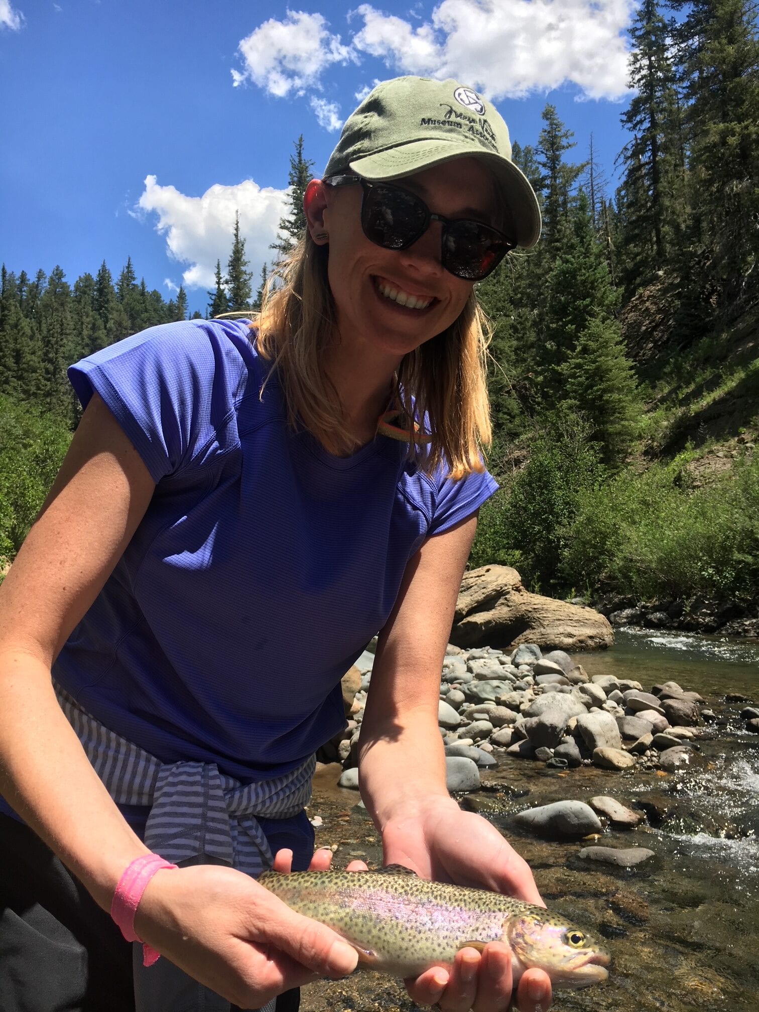 Angler with a rainbow trout under blue skies in the high country near Big Meadows