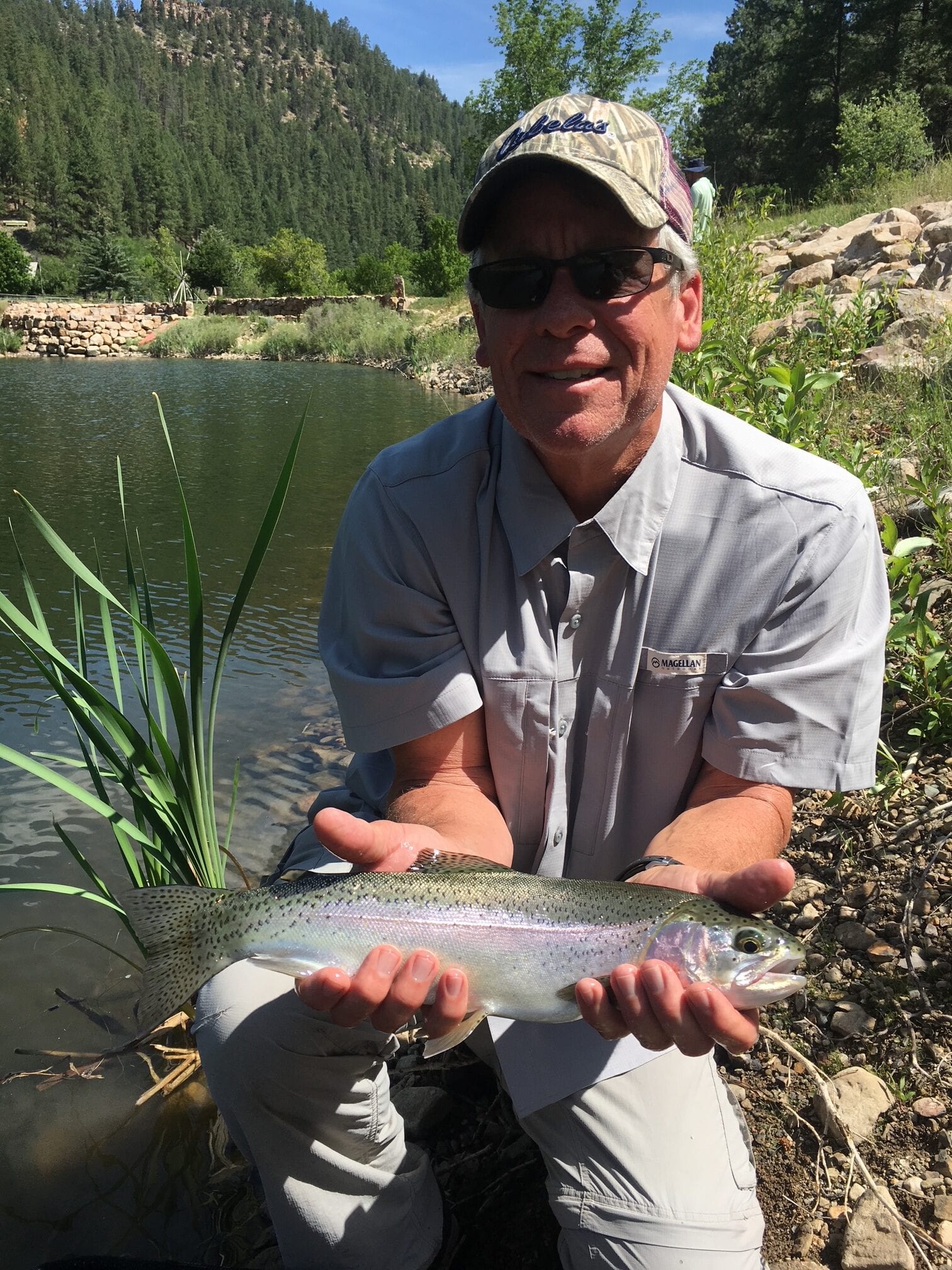 Angler holding a rainbow trout beside a spring-fed pond at Snow Angel Ranch