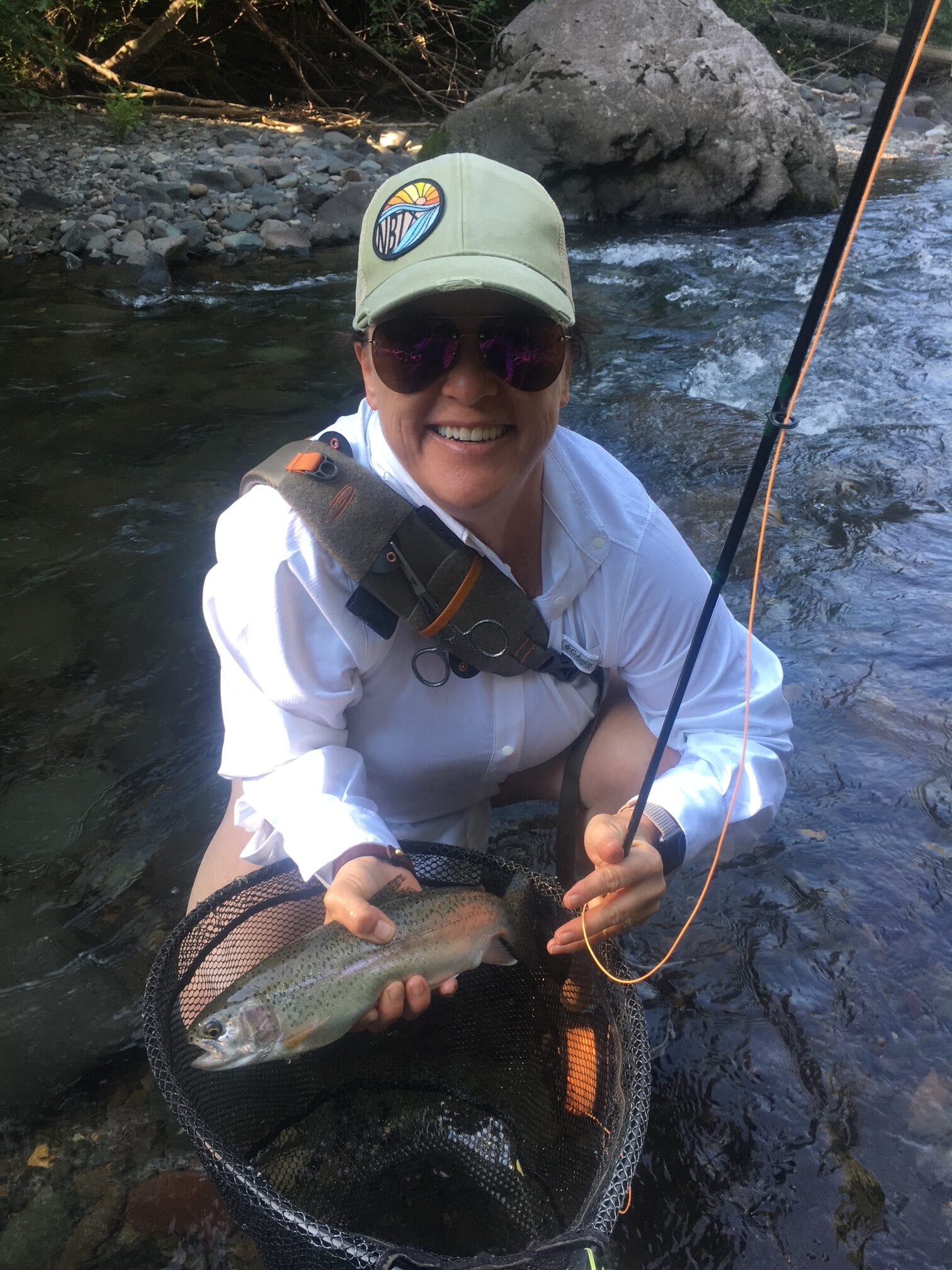 Woman angler netting rainbow trout, guided fly fishing trip near Pagosa Springs, Colorado